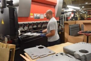 Man using machine to stamp metal sheet
